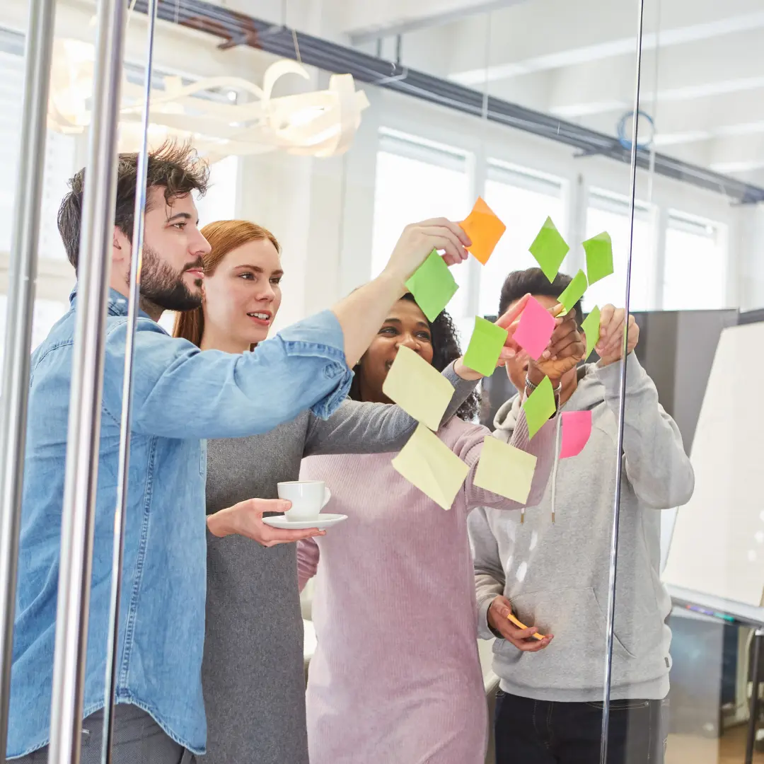Un atelier collaboratif : une équipe pose des post-it sur une paroi vitrée