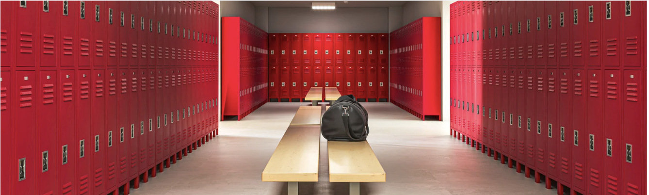 Un vestiaire avec des casiers rouges, un banc central et un sac de sport posé au milieu