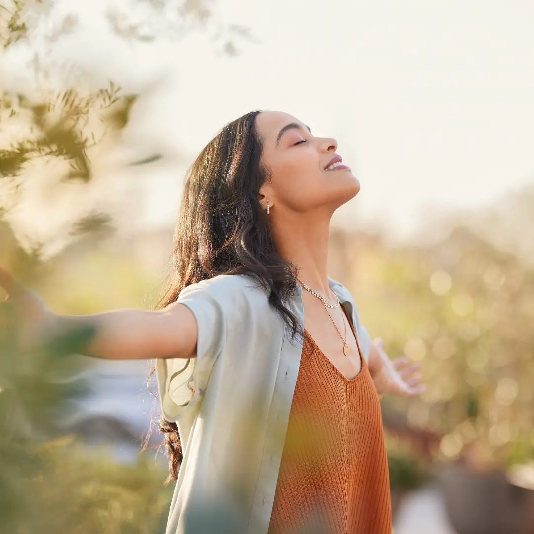 Une femme les bras ouverts au soleil, symbole des immersions et retraites ELBI